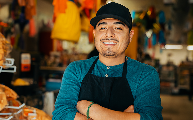 Young business owner smiles proudly while standing in their shop