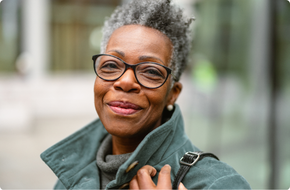 Middle-aged person with kind eyes smiles at camera