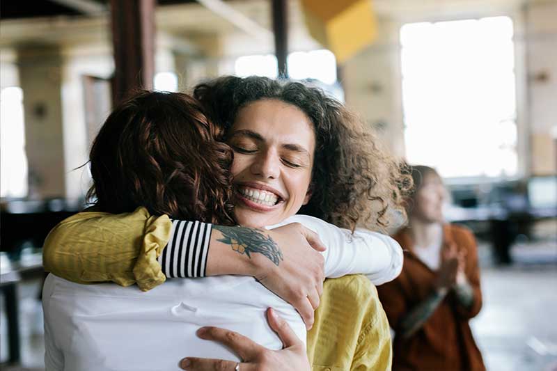 smiling person hugs a friend