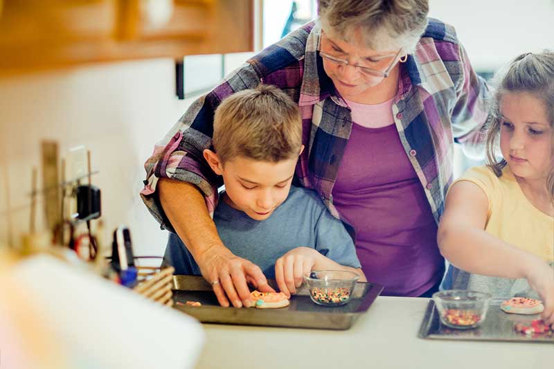 grandmother helps two grandchildren make cookies