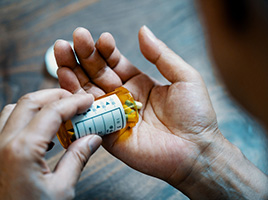 Person pours pills from a prescription bottle into an open hand.