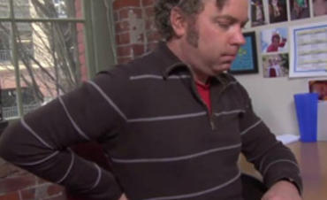 Man sitting at desk holding his back in discomfort