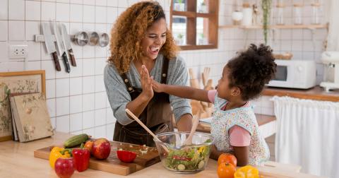 Mother and daughter share a high-five while making a salad